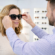 Customer trying on stylish sunglasses with optician assistance in a modern optical store